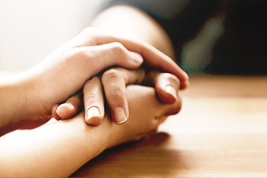 One hand holding another person's hand, providing support and comfort.